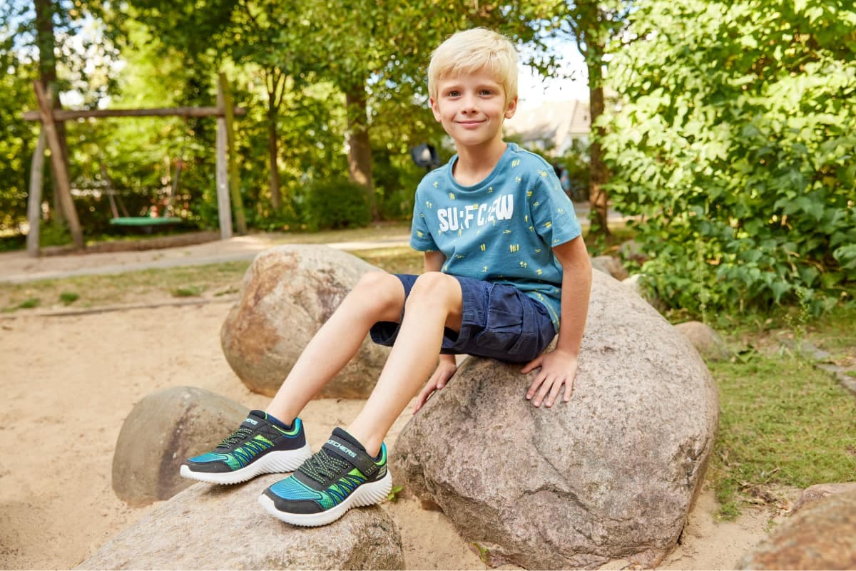 Kleiner Junge sitzt auf einem Stein im Park