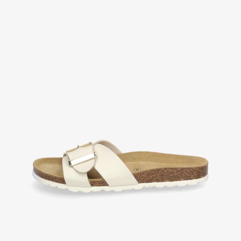 A single beige slide sandal with a cork footbed and a large buckle strap, viewed from the side on a plain white background.